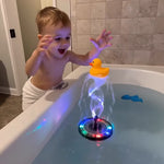 Child playing with a colorful light-up toy in a bathtub