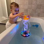 Child playing with a rubber duck in a bathtub featuring a colorful light-up toy.