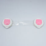 Two white contact lens cases with pink smiley faces on a light gray background